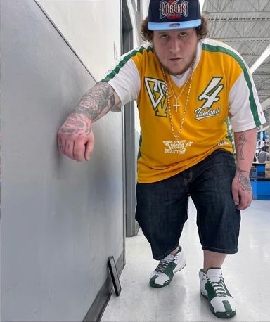 leaning on a wall inside walmart in a yellow jersey